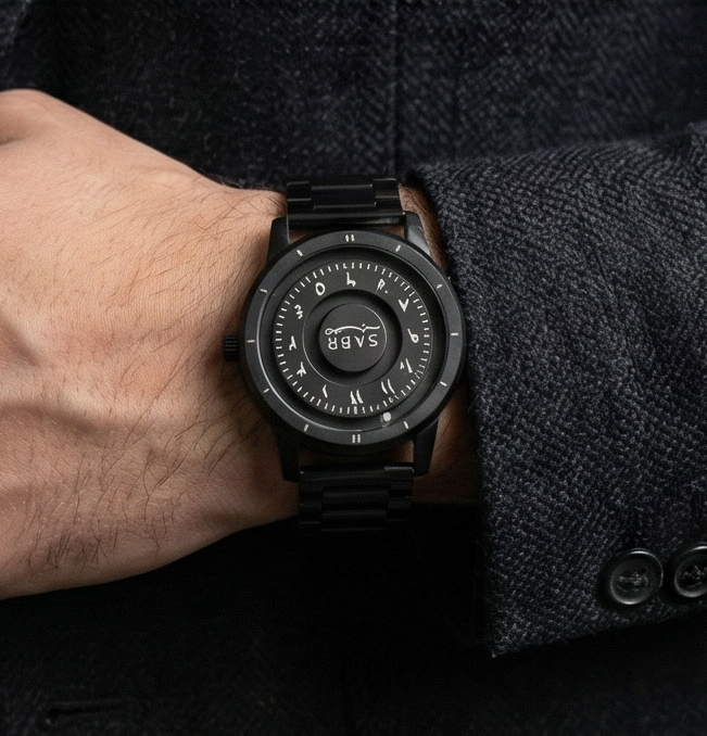 Black sabr watch on a person's wrist with a dark coat sleeve.